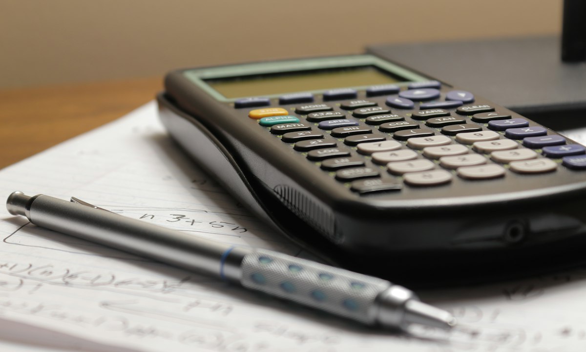 Een rekenmachine en een vulpotlood op een vel met berekeningen. De nacalculatie van je eigen projecten is de data die een nieuwe calculatie beter maakt.