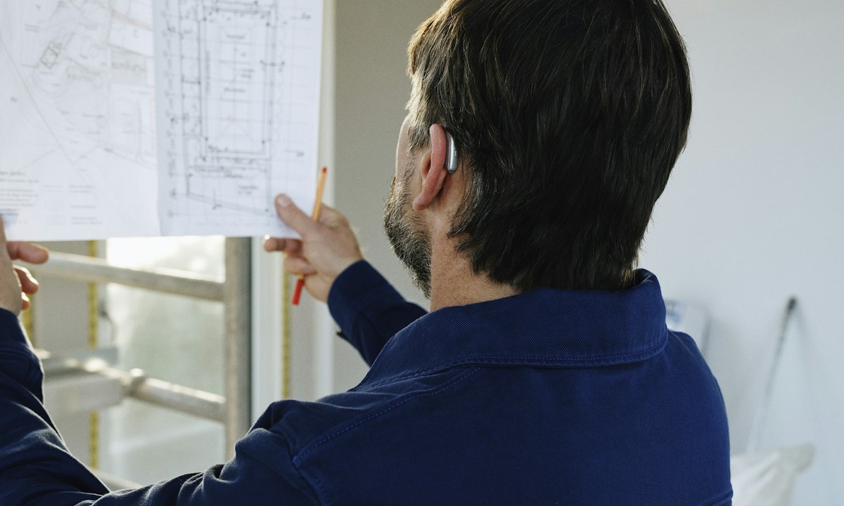 Tekeningen naast elkaar houden in een pand in aanbouw. Een systeem kan tegenstrijdigheden markeren, de calculator beoordeelt welke ertoe doen.