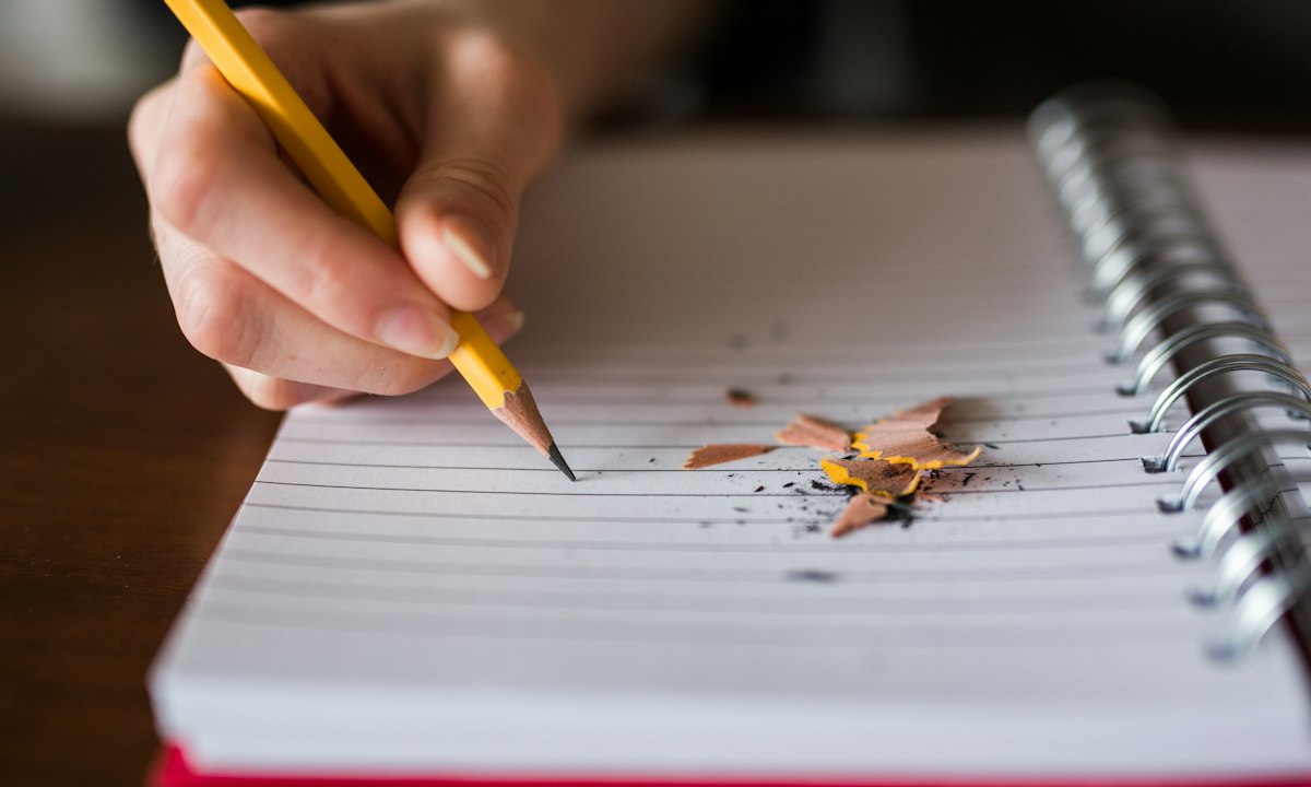 Een hand die in een notitieboek schrijft. Schrijf op wat een scan niet doet voordat je tekent, niet erna.