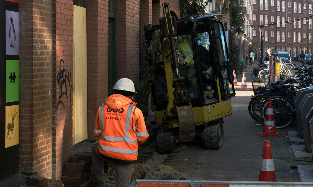 Een bouwvakker naast een vrachtwagen in Amsterdam. In de bouw zit de meeste terug te winnen tijd voor de eerste schep de grond in gaat.