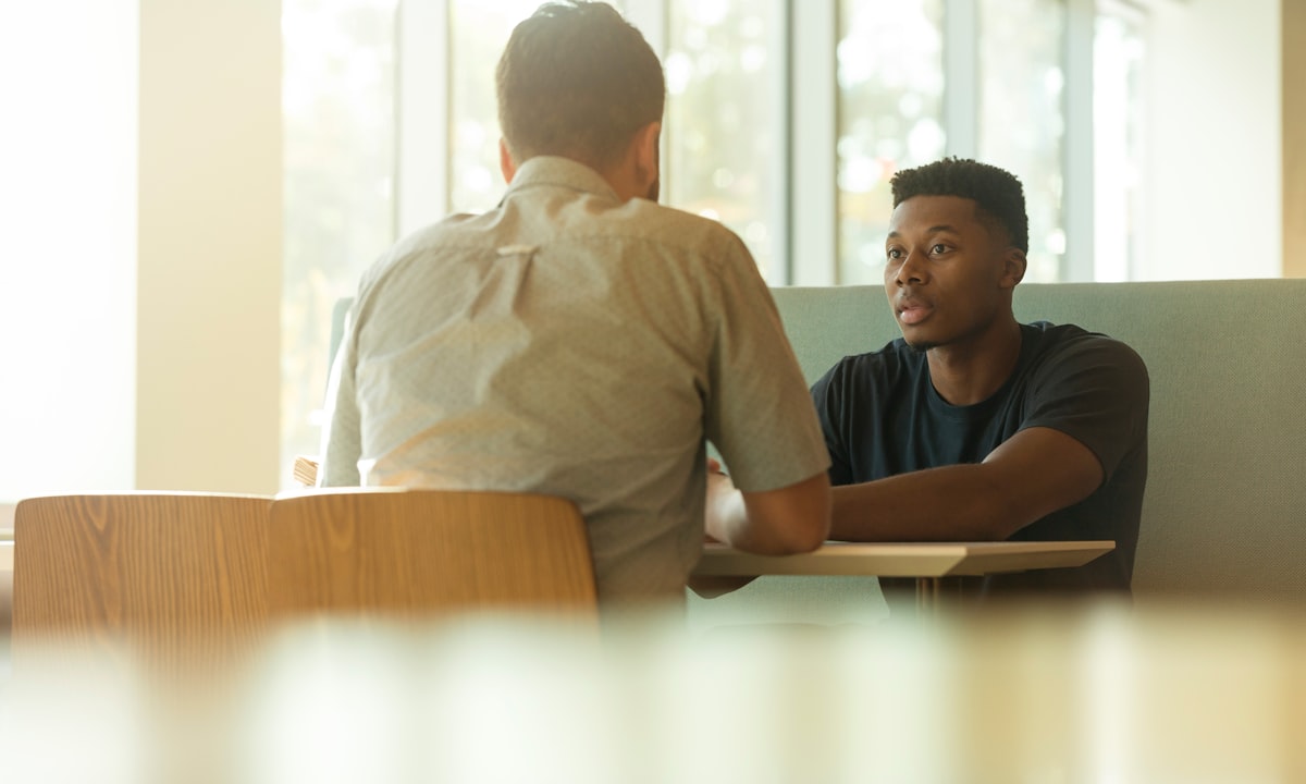 Two people talking. A named person who can explain the decision is the practical answer.