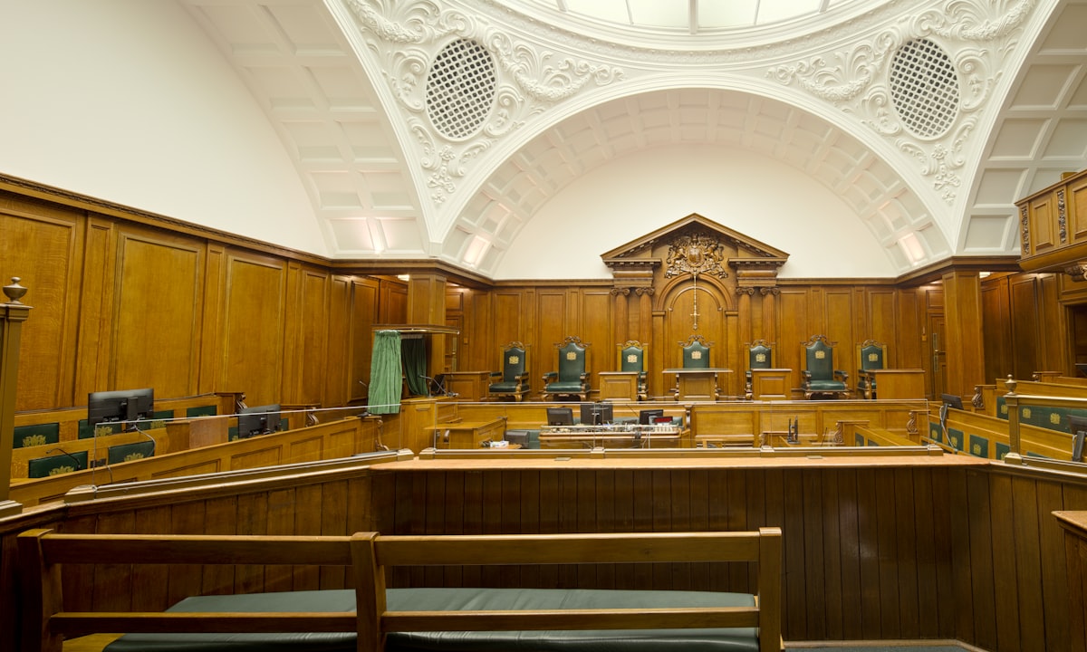 An empty courtroom. The question is not whether someone is liable, but which of three parties.